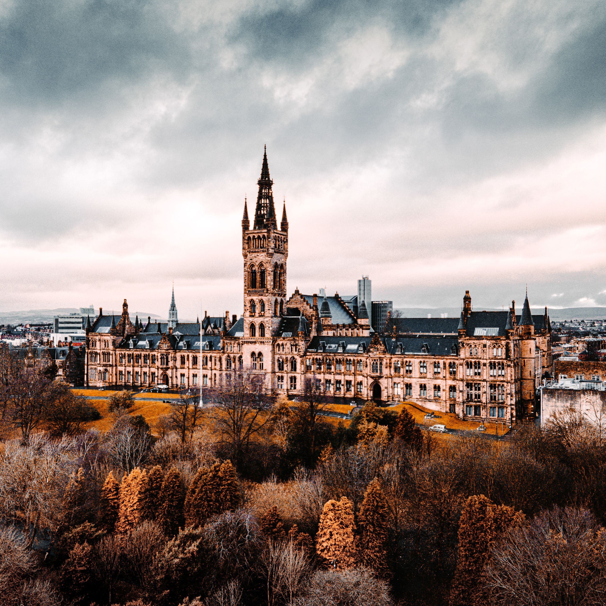 Stunning aerial shot of the University of Glasgow with autumn foliage, showcasing historic architecture.